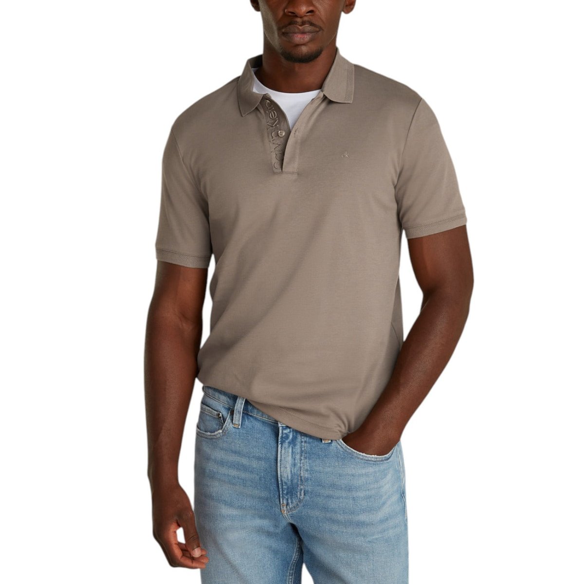 Calvin Klein Polo Uomo in cotone organico marrone, manica corta, ideale per look casual primavera/estate. Abbinata a jeans chiari per outfit moderno.