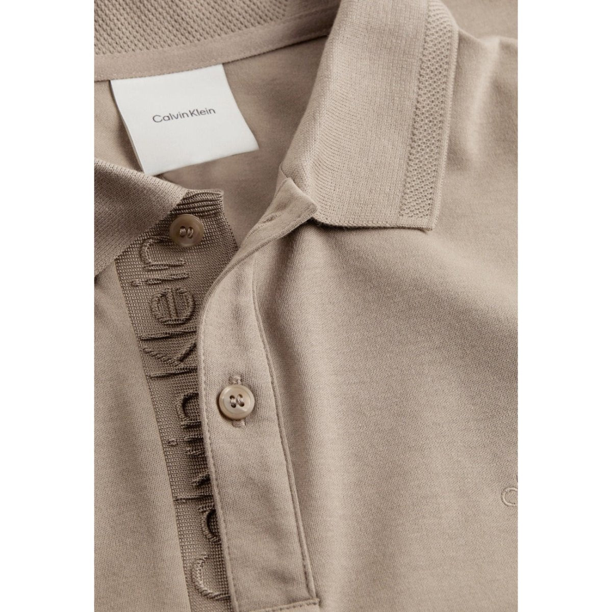 Dettaglio della Calvin Klein Polo Uomo in cotone organico marrone con logo ricamato e bottoni tono su tono. Stile raffinato e sostenibile.